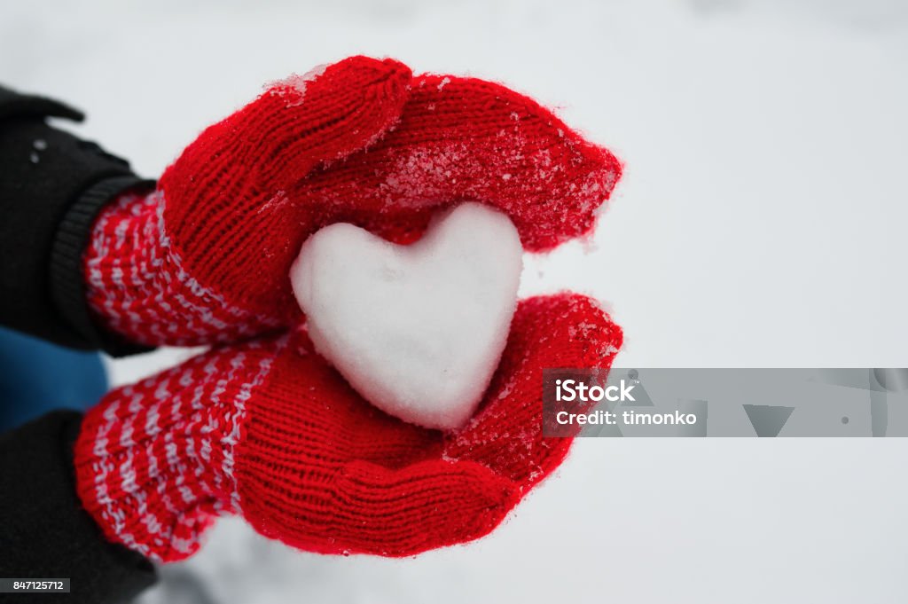 red female gloves hold a white heart from the snow red female gloves hold a white heart from the snow. The concept of love and acceptance Winter Stock Photo