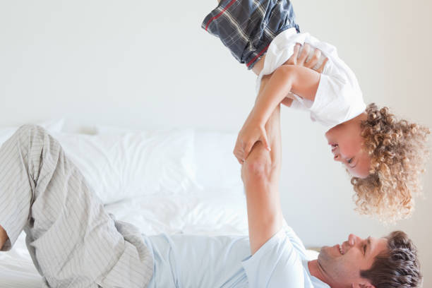 istock Side view of father lifting child on bed 847143744