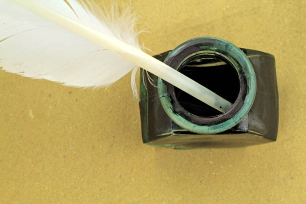istock Quill pen in glass ink bottle on a brown paper 847145648
