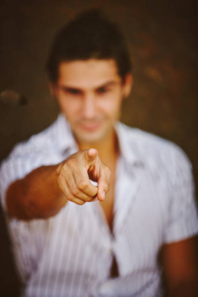 istock Handsome man sitting on the trunk of a tree in a park and pointing with one finger forward 847156140