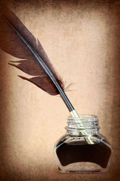 istock Quill pen in ink bottle on brown background. 847169262