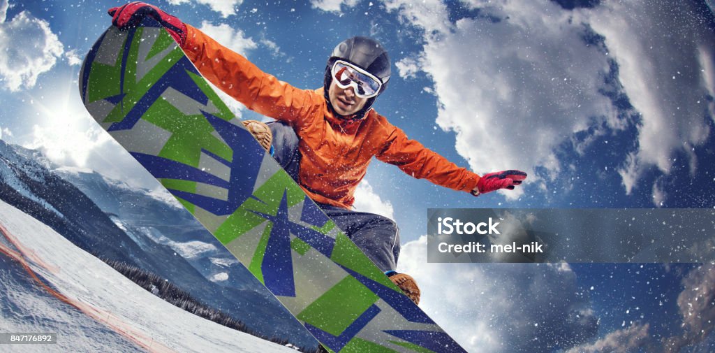 Sport background. Winter sport. Snowboarder jumping through air with deep blue sky in background. Young man jumps with the snowboard in the mountains. Snowboarding Stock Photo