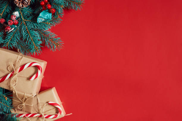 istock Christmas composition of pine cones, spruce branches and stack of gift boxes on red background 847177376
