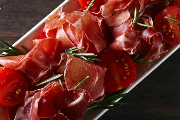 istock Prosciutto with  rosemary and tomato on a wooden table 847182806