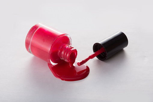 Spilled red nail polish on the floor on white background