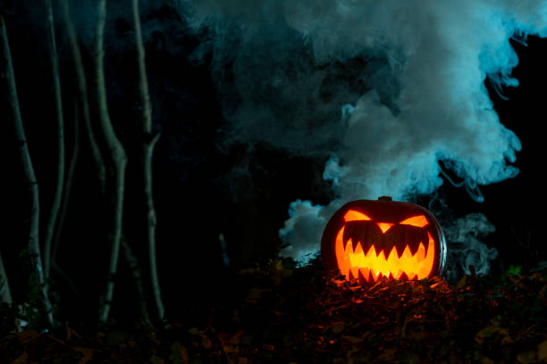 istock Illuminated Carved Pumpkin with Scary Face in Dark Woods 847198754