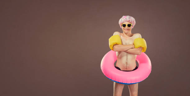 Funny cheerful thin man in a bathing suit with an inflatable circle in pool.