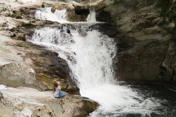 istock Girl sitting on a rock next to the Waterfall 847199630