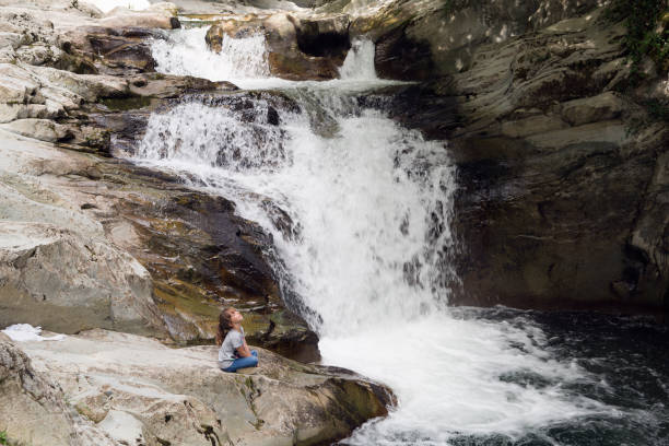 istock Girl sitting on a rock next to the Waterfall 847199644