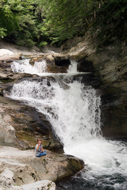 istock Girl sitting on a rock next to the Waterfall 847199648