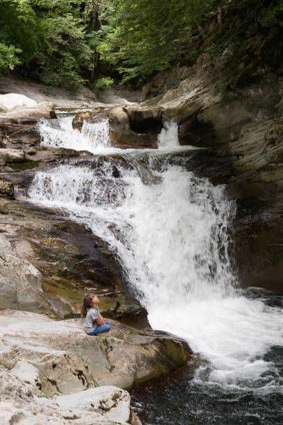 istock Girl sitting on a rock next to the Waterfall 847199658