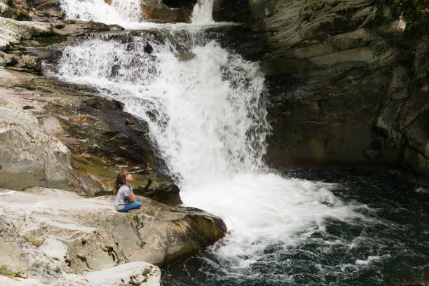 istock Girl sitting on a rock next to the Waterfall 847199662