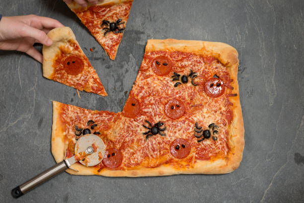 istock Hands Taking Slices of Halloween-Themed Pizza with Pizza Cutter 847202318