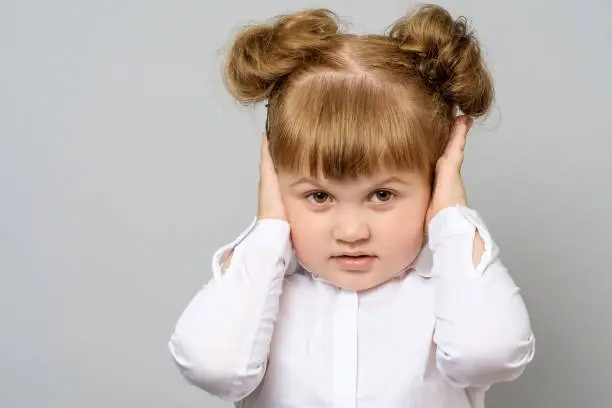 Photo of Disappointed little girl covering her ears isolated