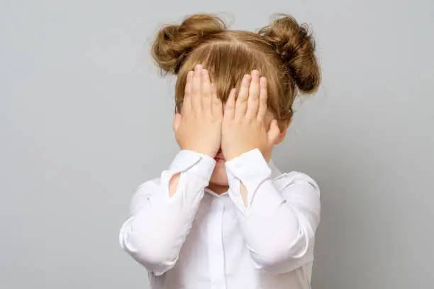 Girl covering her eyes with her hands isolated