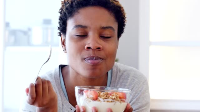 Young African American woman eats bowl of healthy granola