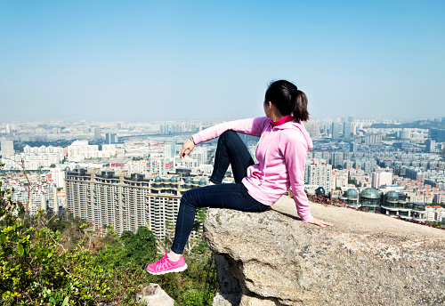 Woman sitting at the edge of mountain peak rock.