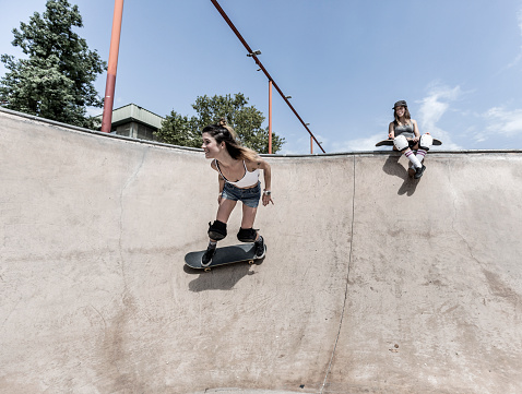 Two young women skateboarding in skatepak