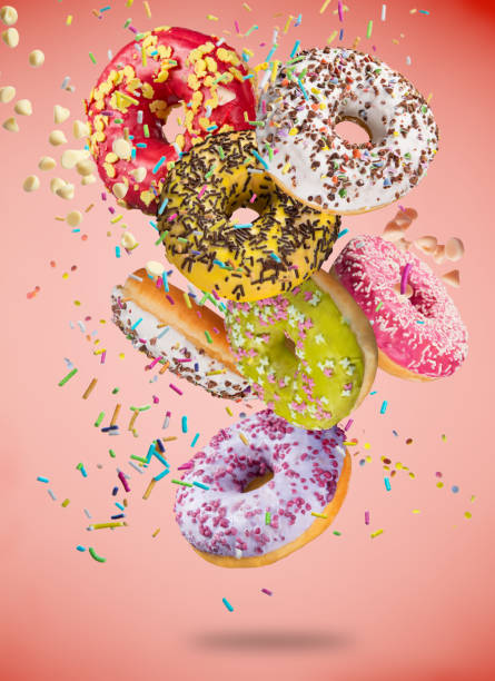 istock Tasty doughnuts in motion falling on pastel red background 847245588