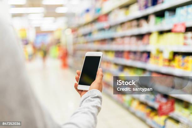 Foto de Feche De Mulher Usando Seu Celular No Supermercado e mais fotos de stock de Supermercado