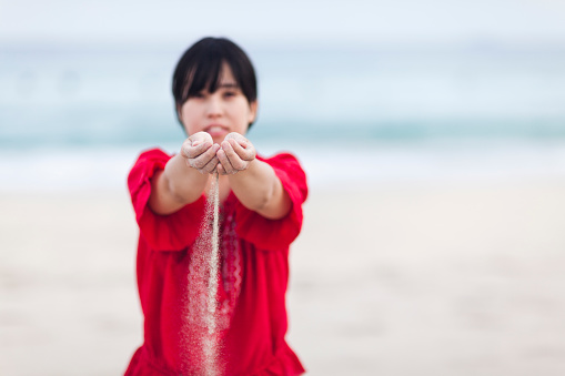 A young Japanese woman is dropping the sand from her hands.