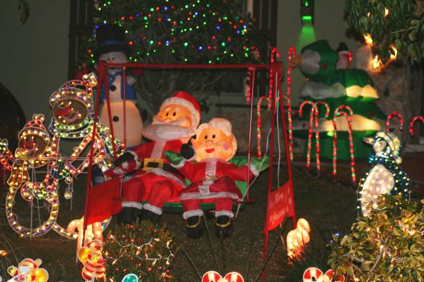 Outdoor Christmas Decorations Busy scene of Christmas decorations outside house; Santa and Mrs Claus sitting on swing; taken in Florida, USA. blow up doll stock pictures, royalty-free photos & images