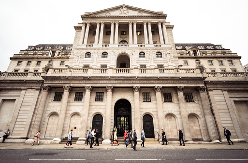 London, UK - Pedestrians on Threadneedle Street passing the imposing facade of the Bank of England, the United Kingdom's central bank, located in the City of London.