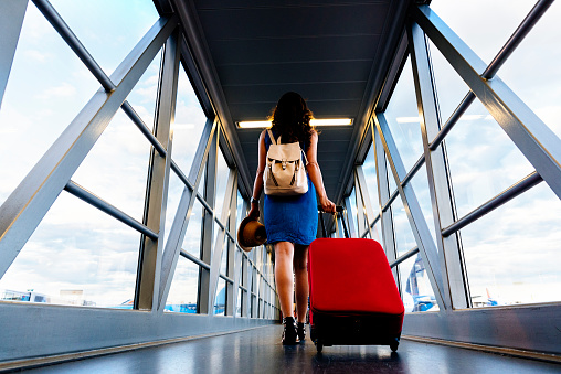 Viajero de niña caminando con llevar maleta de espera en el aeropuerto. photo