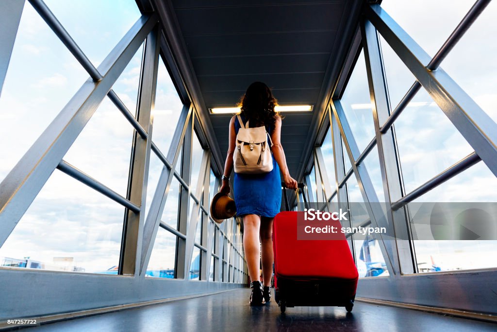 Young girl traveler walking with carrying hold suitcase in the airport. Young girl traveler walking with carrying hold suitcase in the airport. Tourist Concept. Airport Stock Photo
