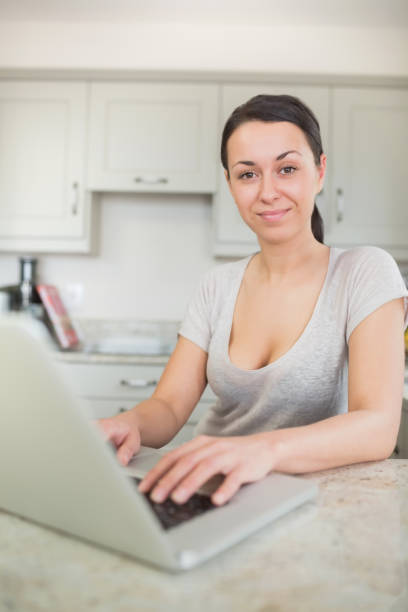 istock Woman typing on laptop in the kitchen 847260176