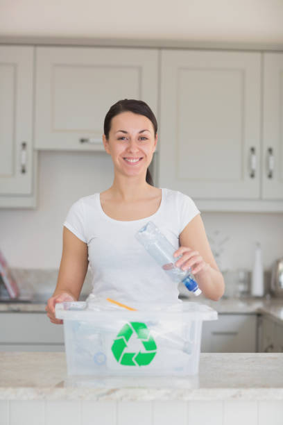 istock Smiling woman throwing bottle into recycling bin 847260538