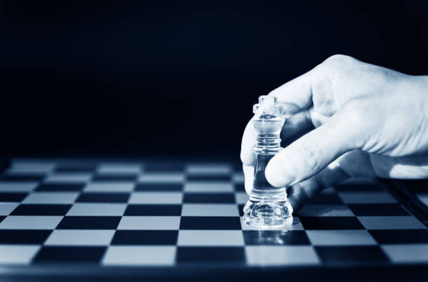 Human hand holding king chess on the black background