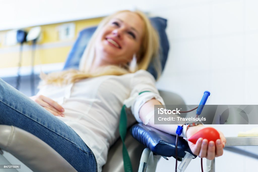 young caucasian woman with toy heart in the hand donates blood for saving lives and medical research young caucasian woman with toy heart in the hand donates blood for saving lives and medical research in some hospital at day time Blood Donation Stock Photo