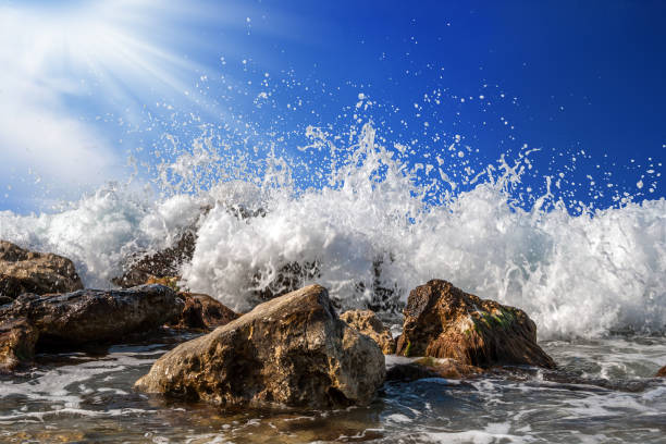 istock Splashing sea water on rocks isolated on a bright blue sky background 847271832
