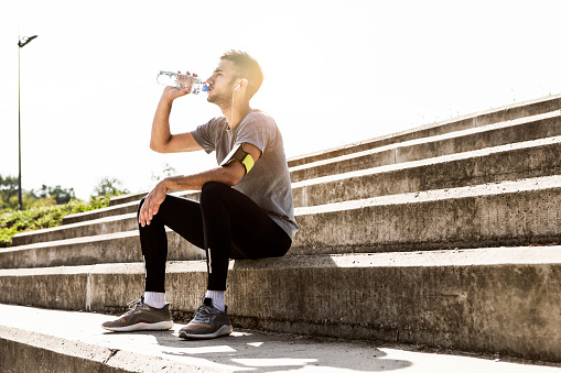 Athlete sitting and resting on the staircase ,drinking water