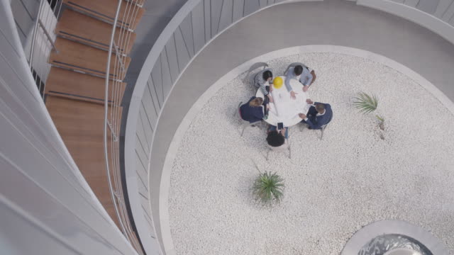 Architects working at table in modern office atrium courtyard near fountain