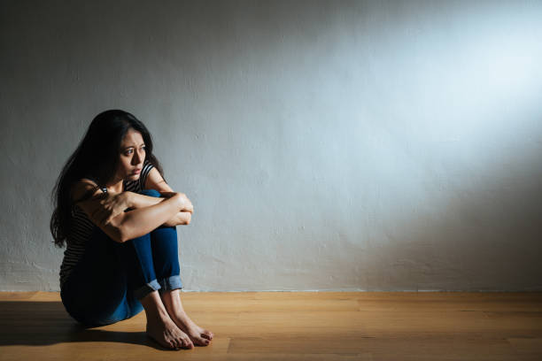 sadness young woman sitting on wood floor - violence domestic violence victim women imagens e fotografias de stock