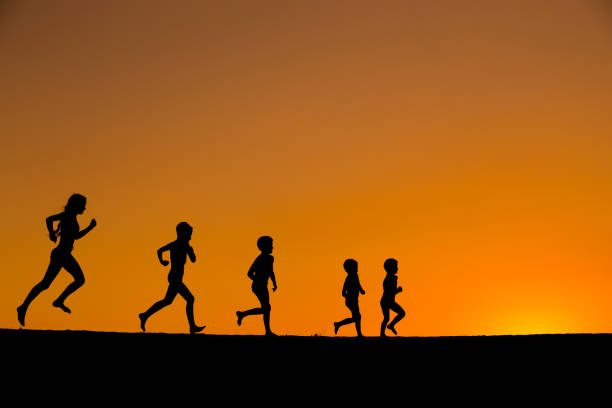 istock silhouette of five running kids against sunset 847290466