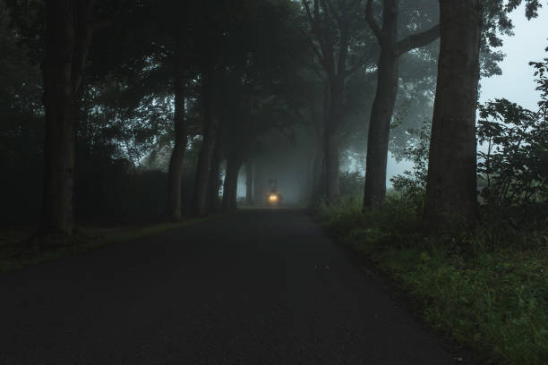 istock Misty country road with tractor and illuminating headlights. 847296840
