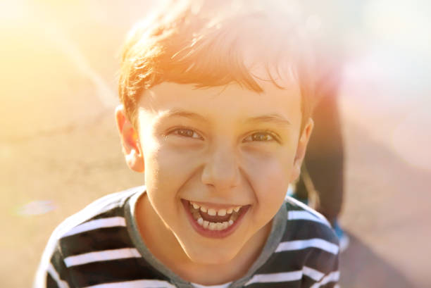 ładny młody 6-7 lat chłopiec uśmiecha się, słoneczne światła, koncepcja dzieciństwa - 6 7 years lifestyles nature horizontal zdjęcia i obrazy z banku zdjęć