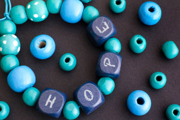 Bracelet with blue wooden beads with letters H O P E. Black background.