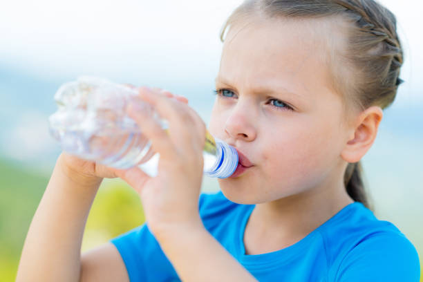 istock little girl drinking fresh water from bottle on light nature background 847327330