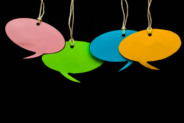 istock Blank white speech bubbles hanging from a cord in front of a black Board 847329656