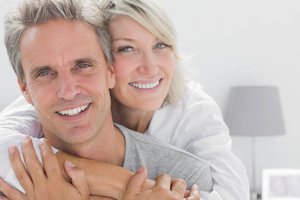 Affectionate couple smiling Affectionate couple smiling at camera at home in bedroom mature couple photos stock pictures, royalty-free photos & images