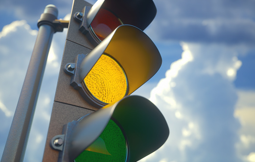 Traffic light with yellow light on, signal for proceed with caution.