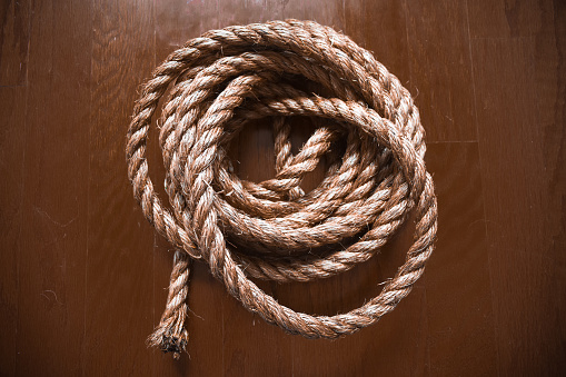Twine rope in circle against wood backdrop.