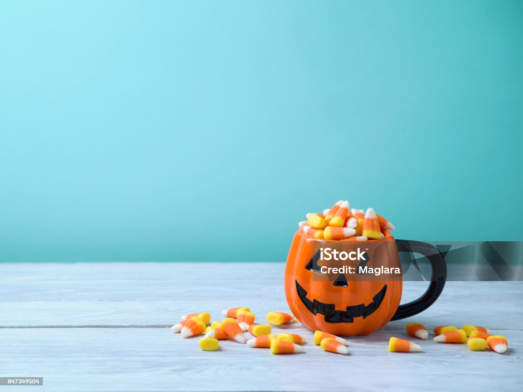 Halloween celebration concept with candy corn Halloween celebration concept with candy corn and jack o lantern cup on wooden table. Candy Corn Stock Photo