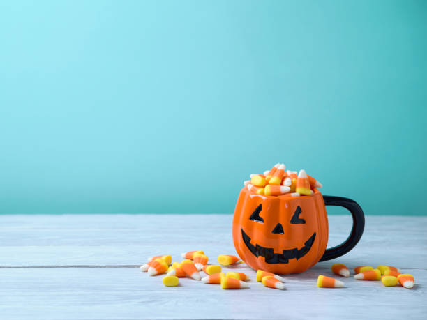 Halloween celebration concept with candy corn Halloween celebration concept with candy corn and jack o lantern cup on wooden table. candy corn stock pictures, royalty-free photos & images