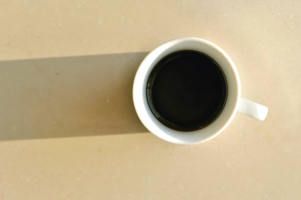 istock Cup of coffe on a bright surface illuminated by the sunlight 847350272