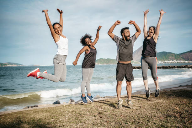 quatre amis brésiliens sautant sur la plage de rio avec le mont du pain de sucre - sugarloaf mountain flash photos et images de collection